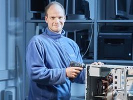 Ein Monteur bei der Arbeit. Er schraubt ein technisches Gerät auf.